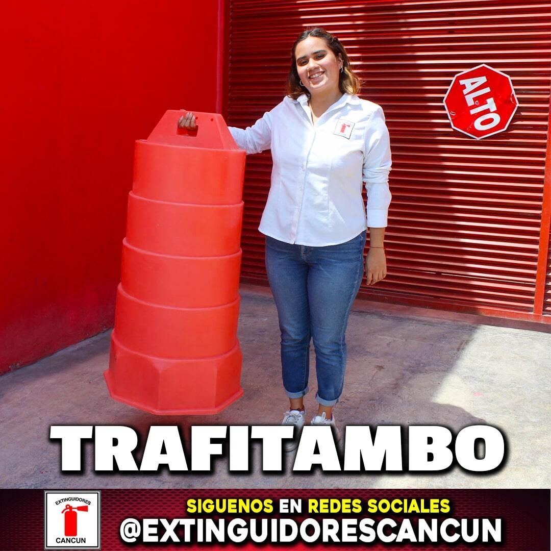 Una mujer sostiene un cono rojo frente a un edificio rojo.
