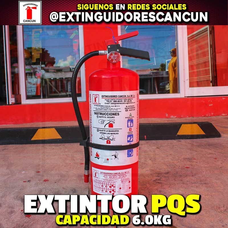 Un extintor de incendios rojo está sentado frente a un edificio rojo.
