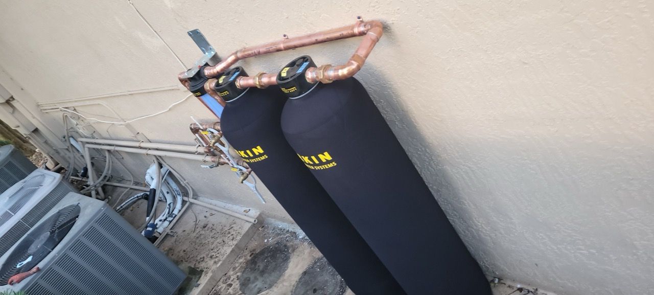 Person in black pants climbing over a wall using a metal ladder, outdoors.