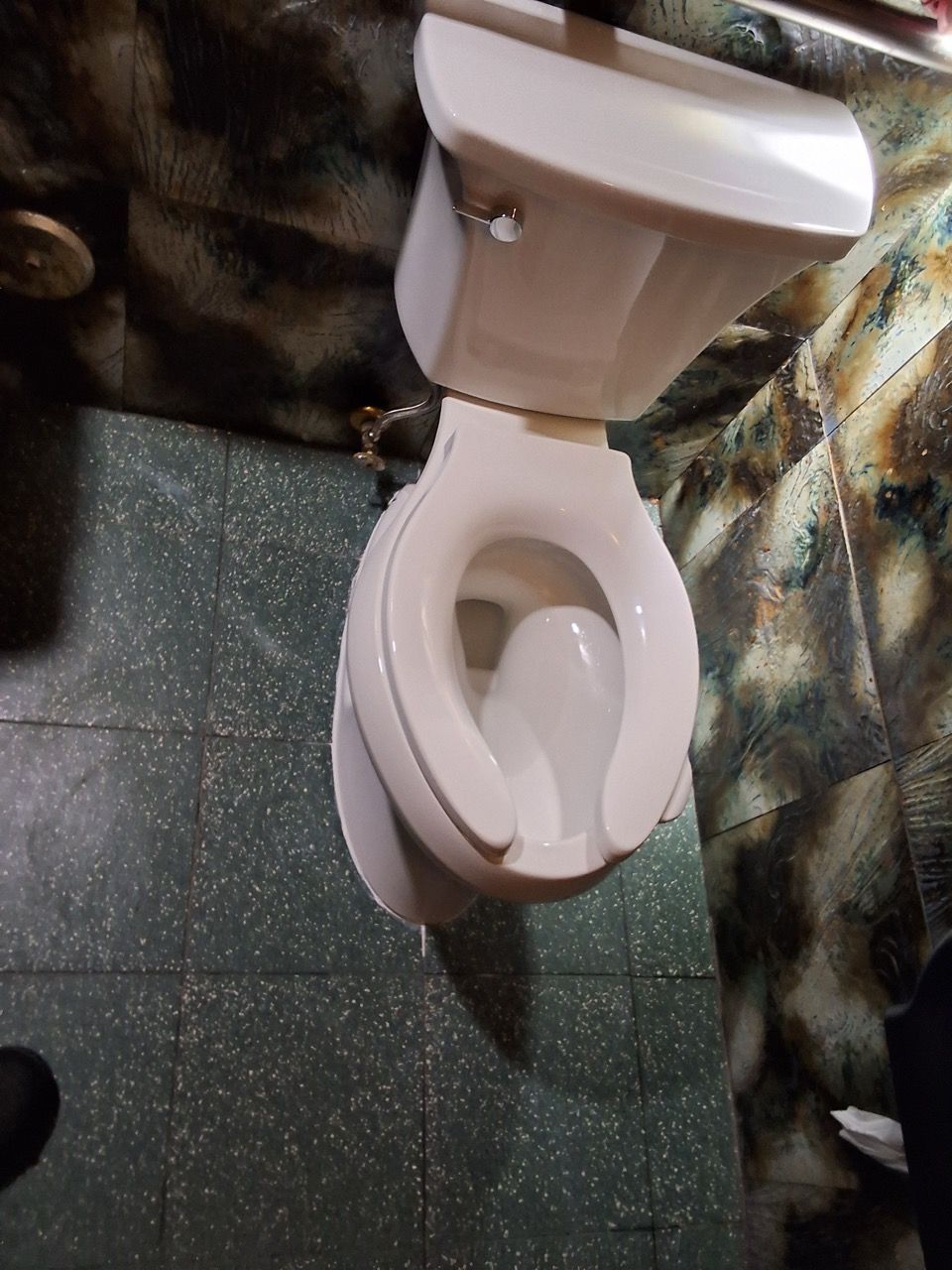 Toilet with the lid and seat raised in a small tiled bathroom