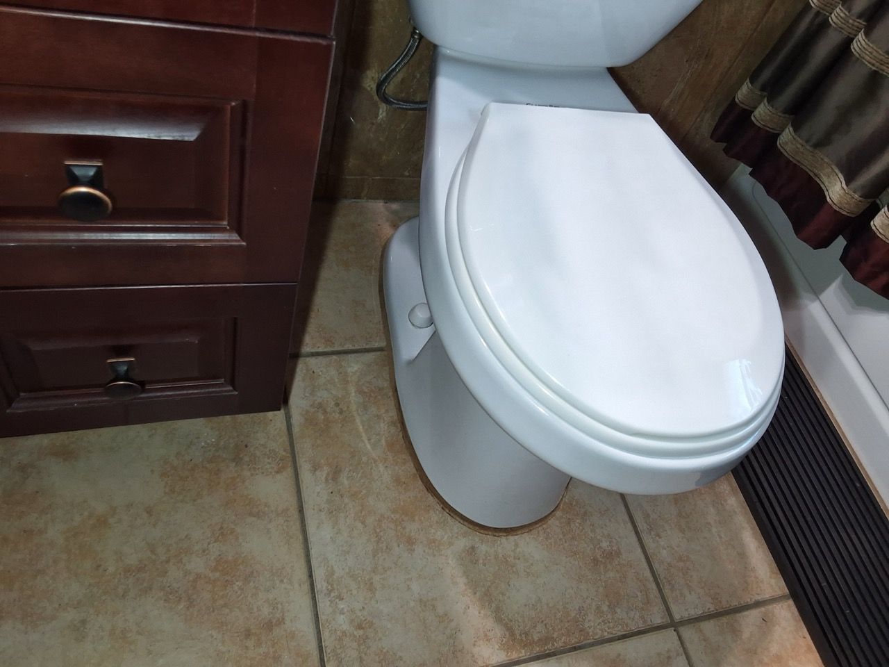 White toilet beside a dark wood vanity on a tiled bathroom floor
