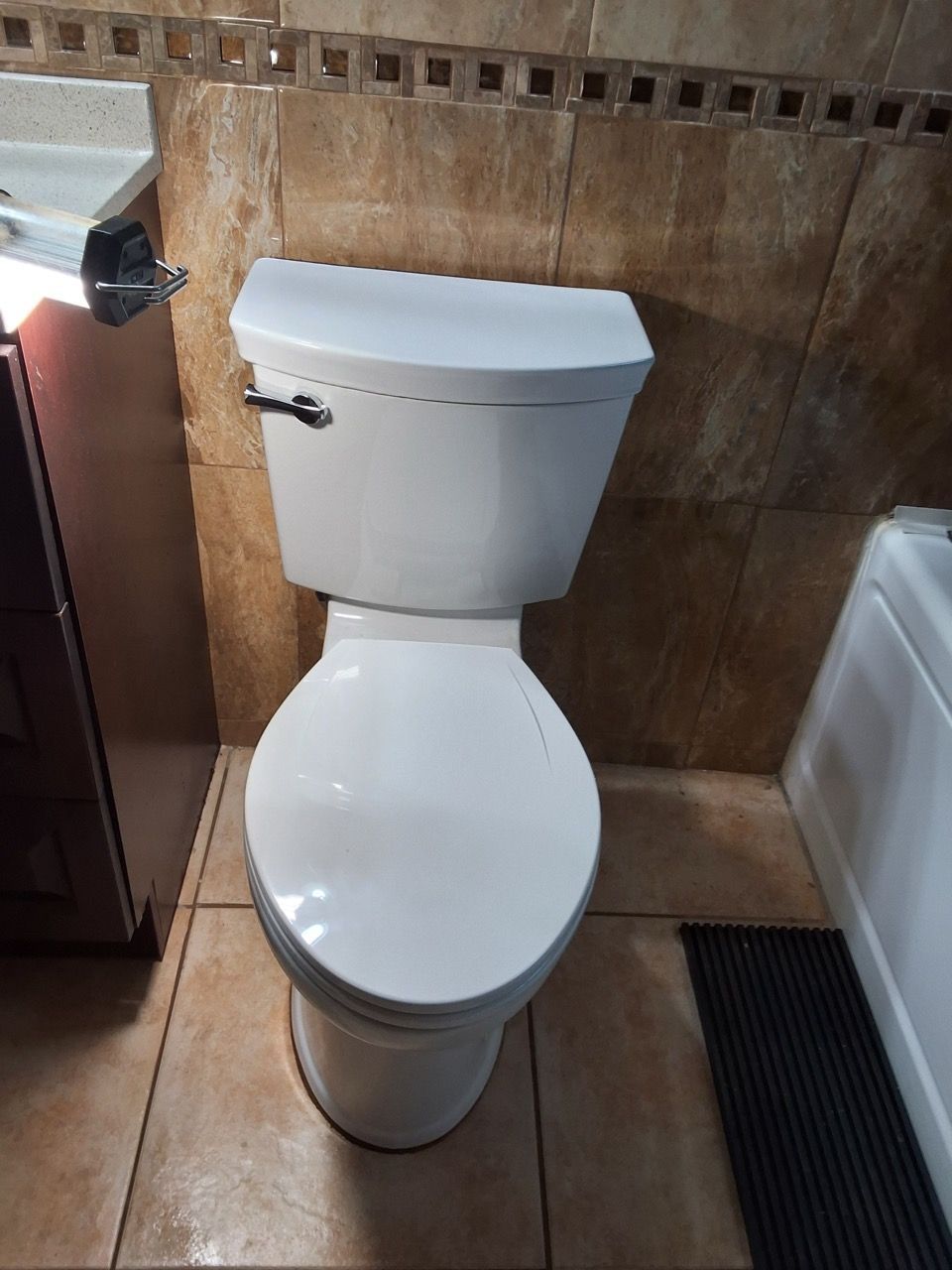 White toilet in a tiled bathroom stall, viewed from above.