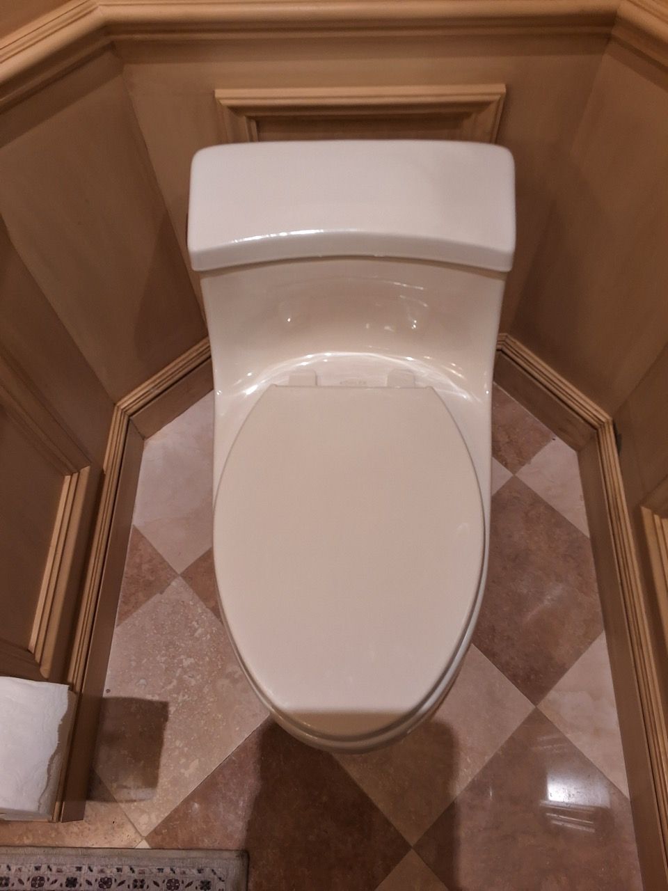 White toilet in a beige-tiled bathroom, viewed from above.