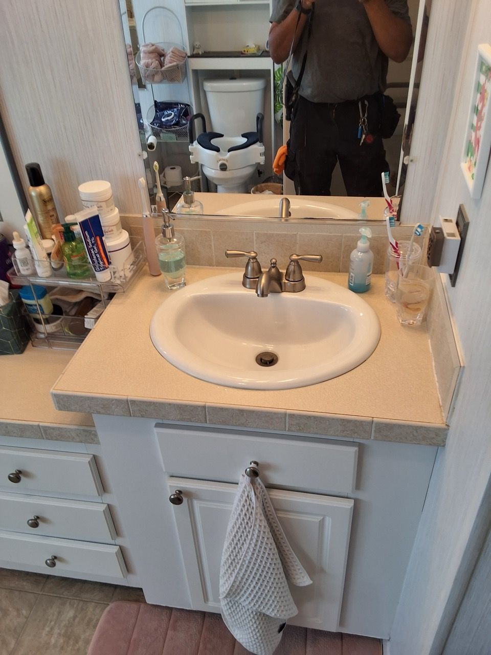 Bathroom vanity with sink, mirror, and toiletries, plus a towel hanging on the cabinet door.