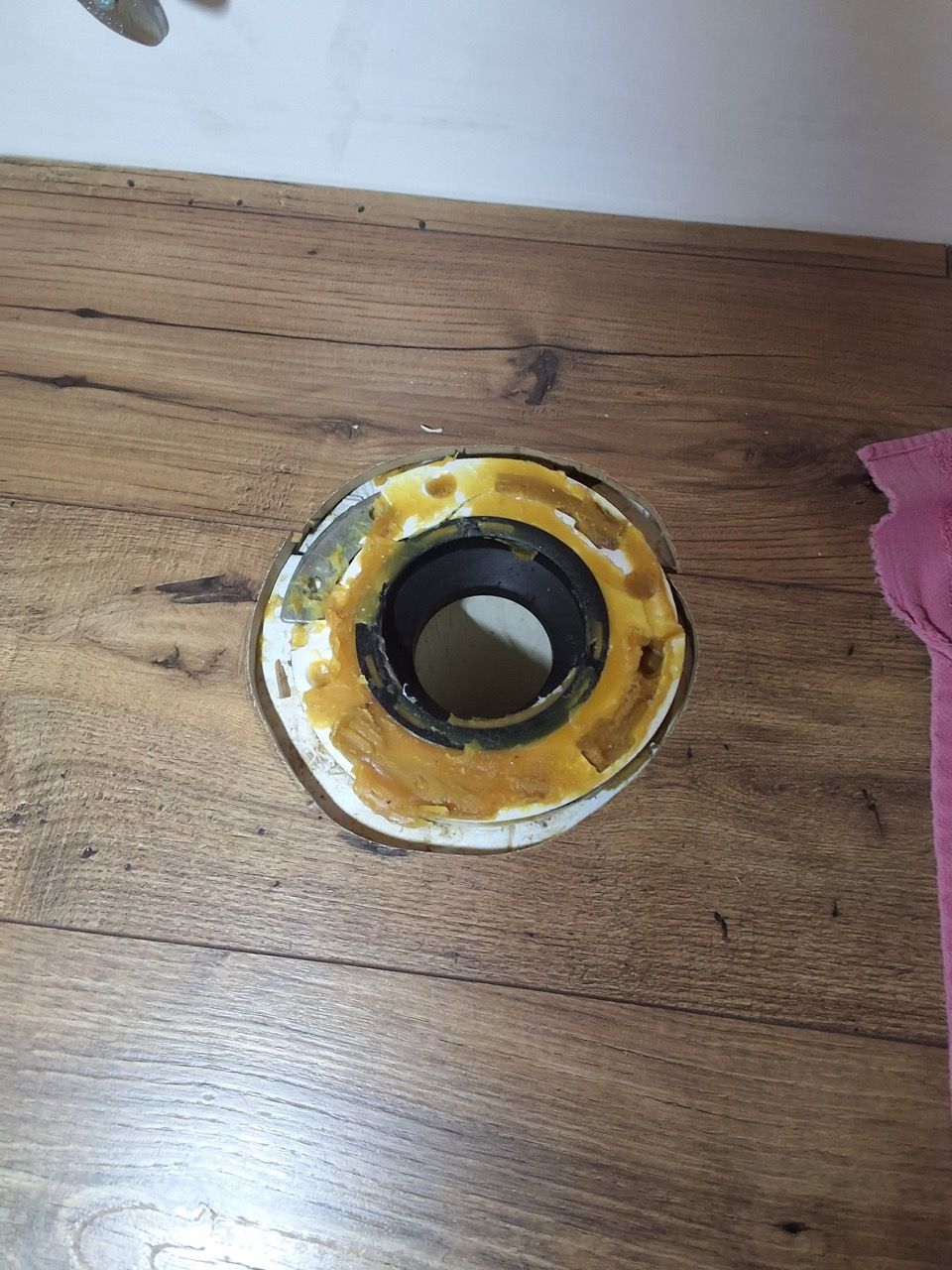 Yellow metal ring around a circular hole in a wooden tabletop, with a pink cloth at the edge.