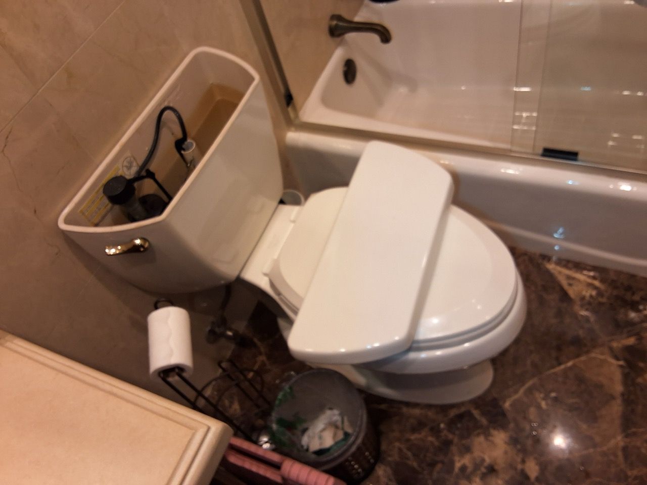 Small bathroom with an oversized toilet tank beside a bathtub and tiled floor.