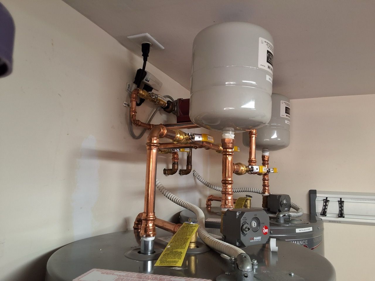 Water heater and copper plumbing pipes installed in a utility room.