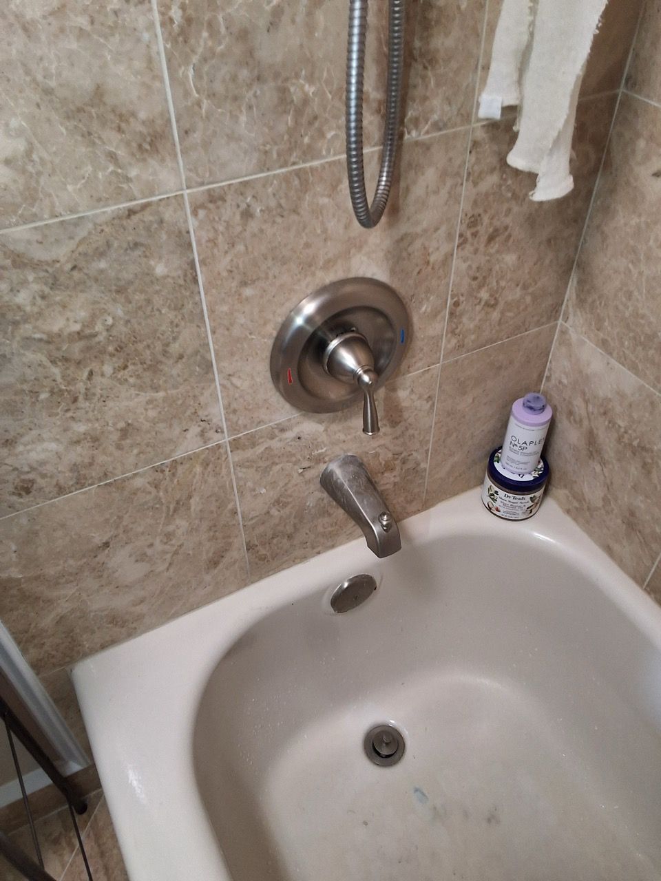 Bathroom sink and wall-mounted faucet with beige tile backsplash and a soap dispenser on the counter.