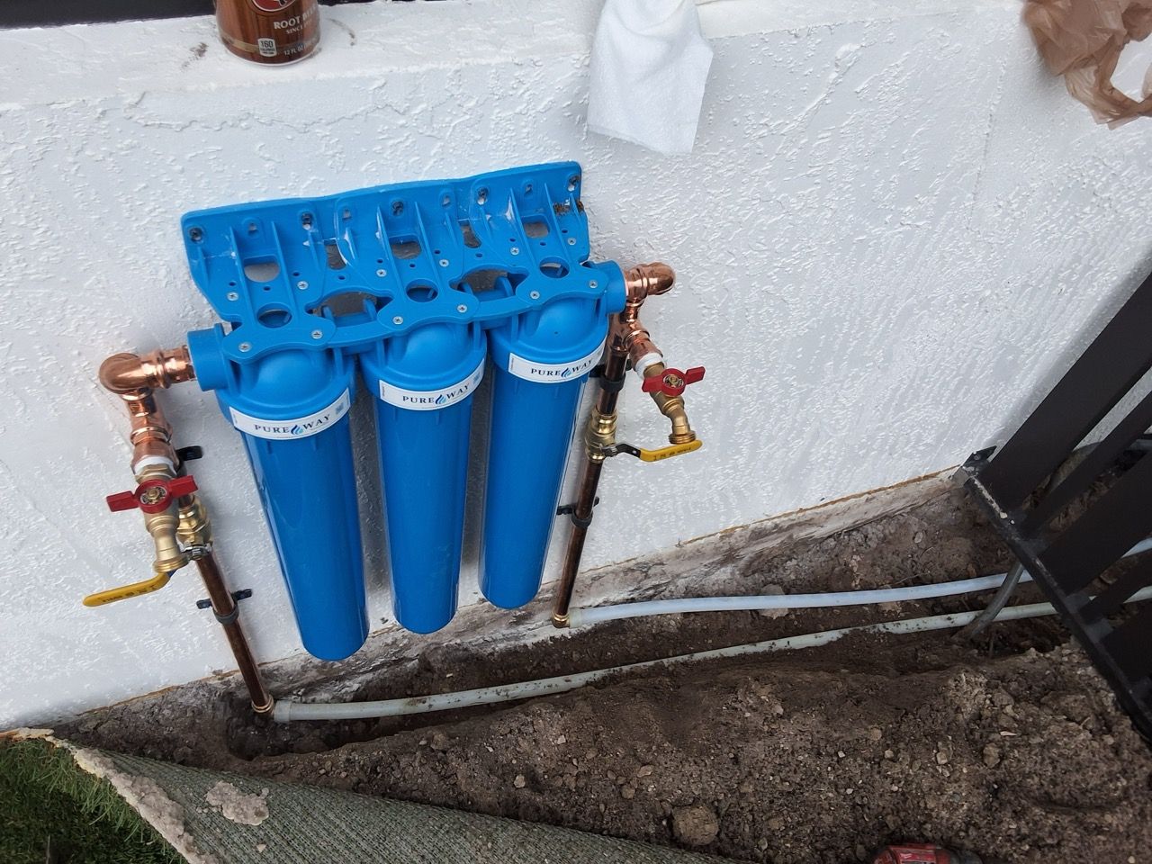 Water heater with expansion tank and copper pipes in a garage-like utility room.