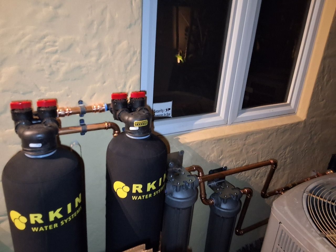 Two black air tanks and two small cylinders beside a window and outdoor AC unit.