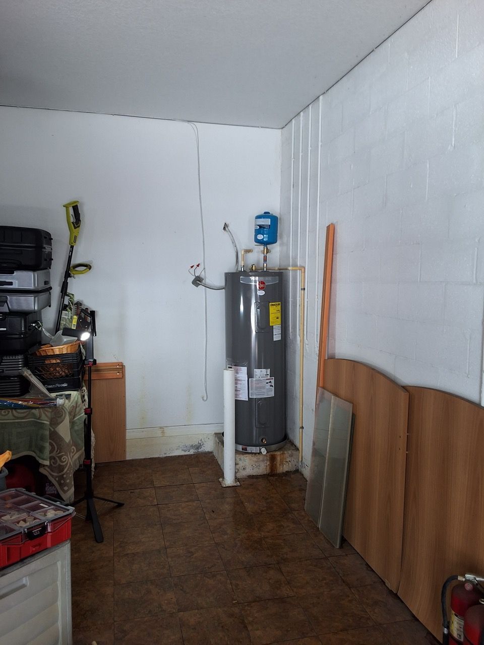 Small utility room with a water heater, white walls, brown paneling, and shelves on the left.