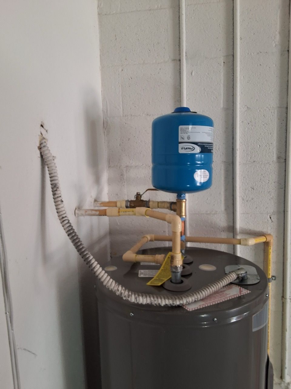 Water heater with blue expansion tank and coiled pipe in a utility room