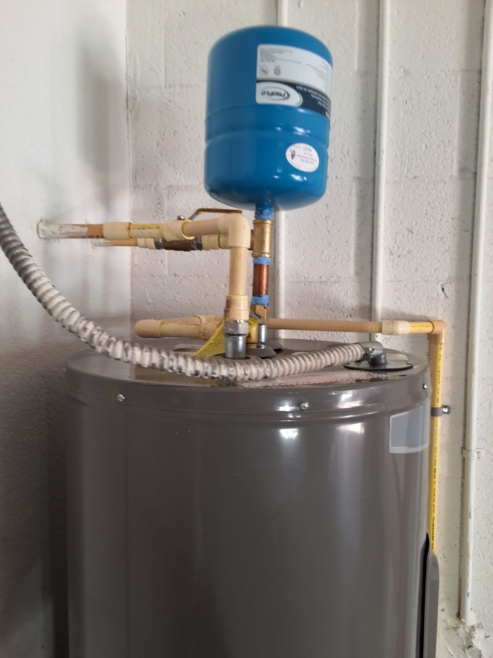 Blue water treatment tank with pipes and a metal base in a utility room