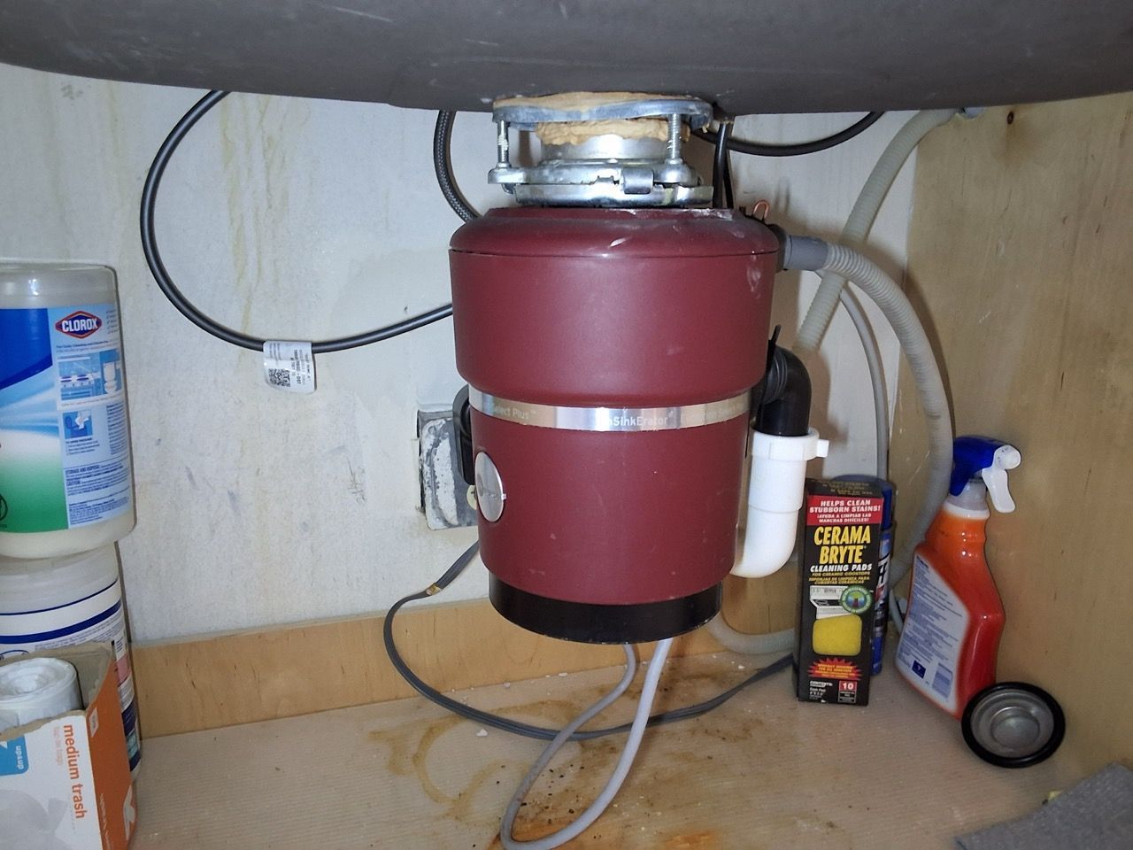 Under-sink disposal unit with cleaning supplies stored beside it