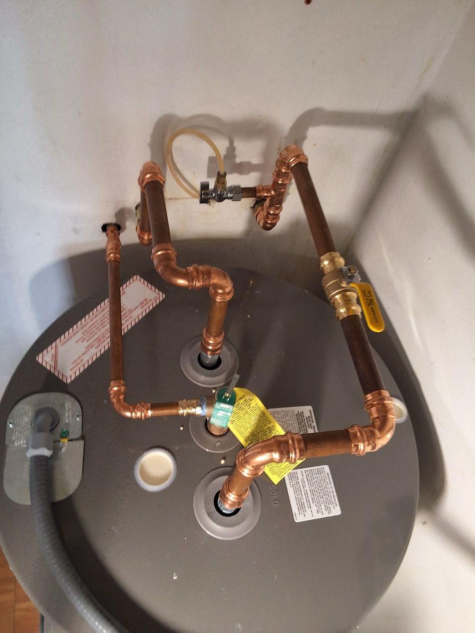 Copper plumbing pipes and valves installed on top of a gray water heater tank