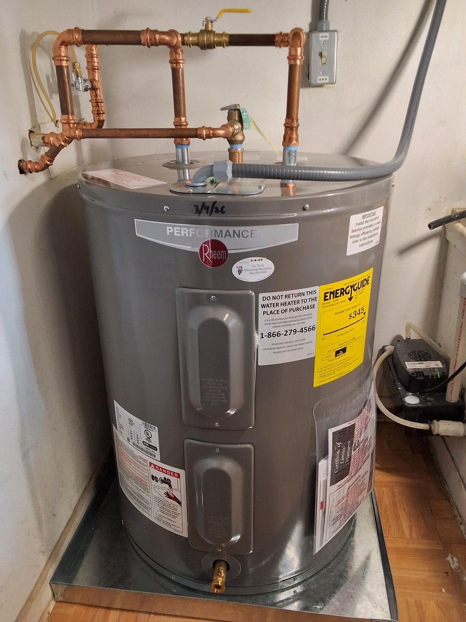 Gray water heater with copper pipes and safety labels in a utility room