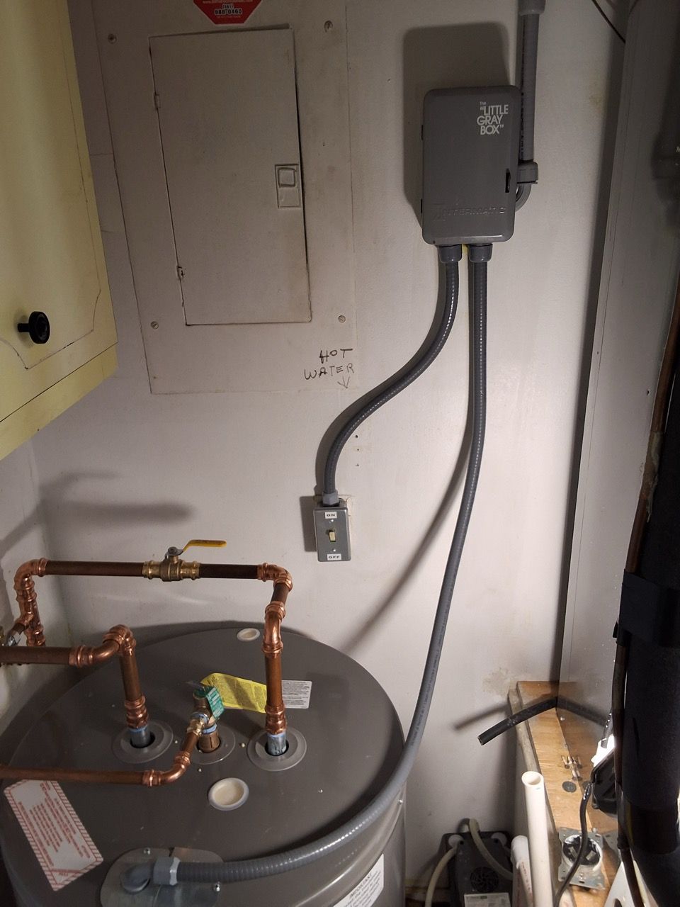 Water heater with copper pipes and electrical box in a utility closet.