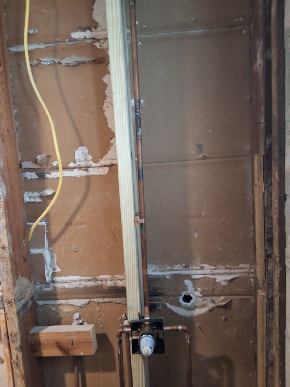 Exposed wall framing with electrical wiring and a pipe during interior construction.