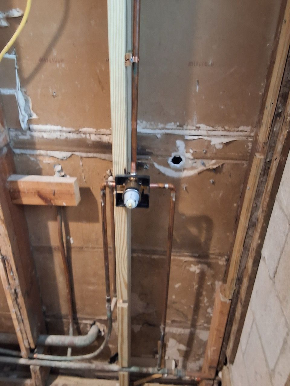 Exposed ceiling framing with wiring and a small mounted sensor or light fixture in a utility space
