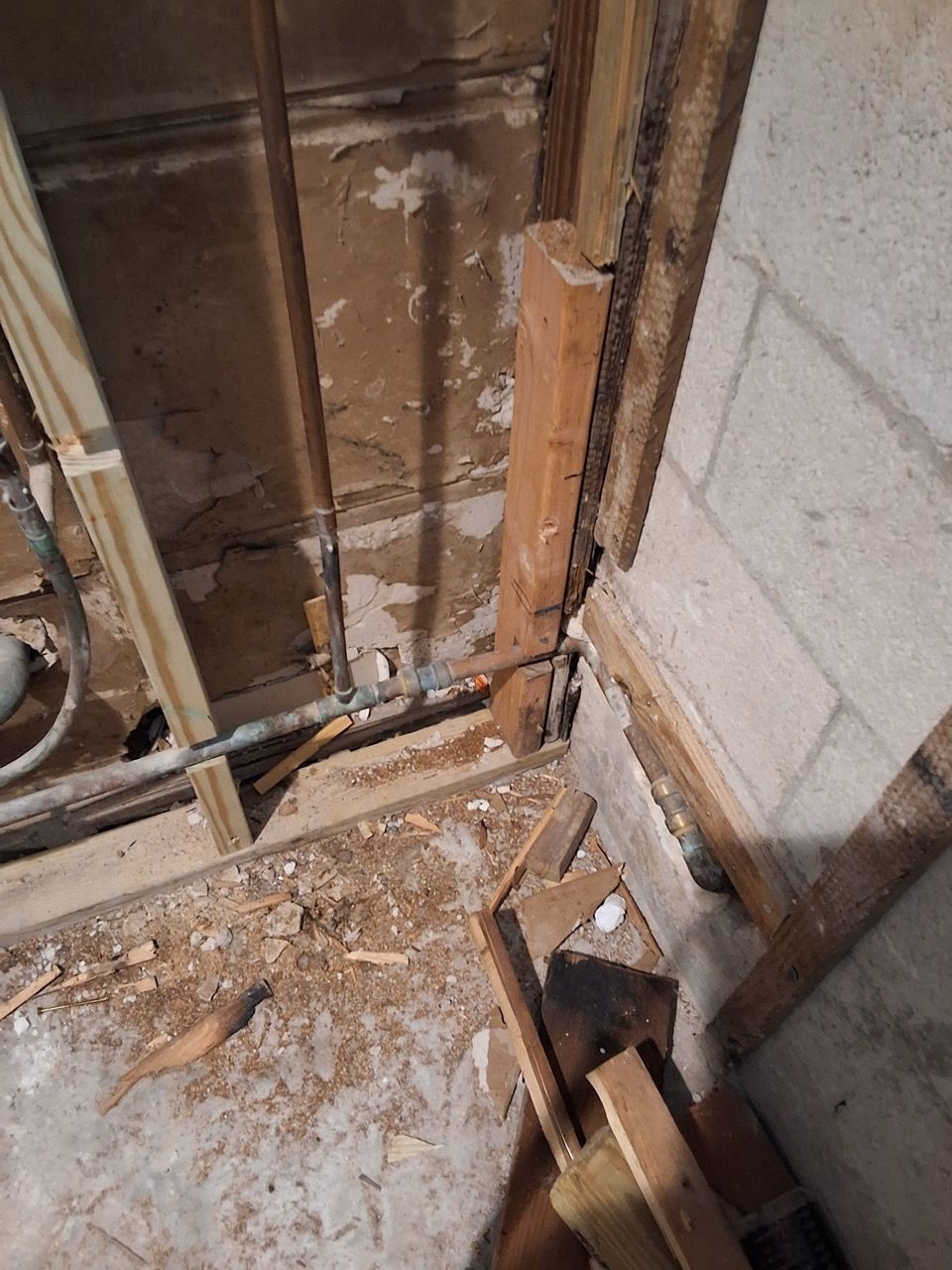 Damaged wall framing and debris in a stripped interior room, with exposed studs and insulation.