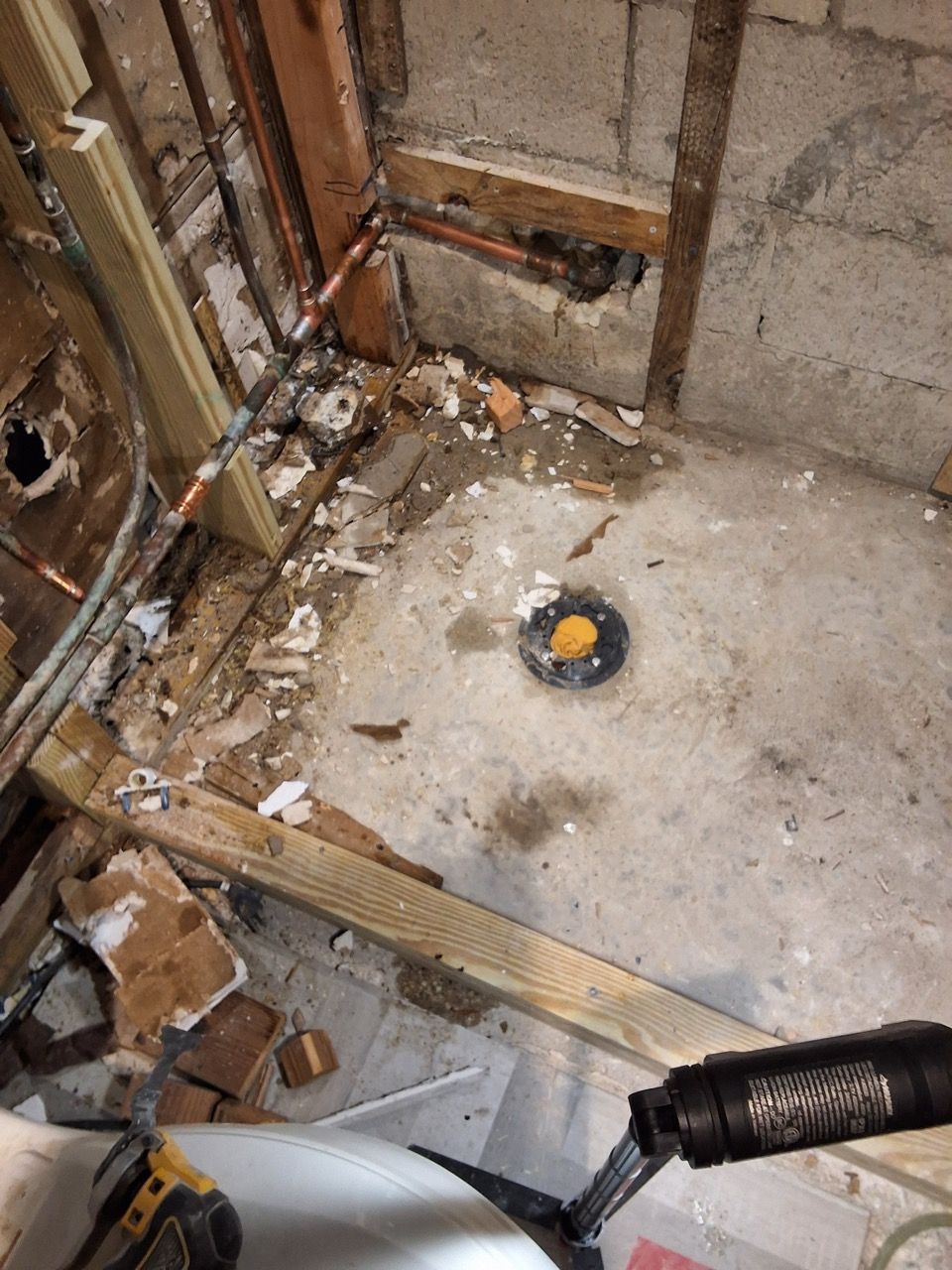 Damaged room floor with debris and exposed framing around a central floor drain