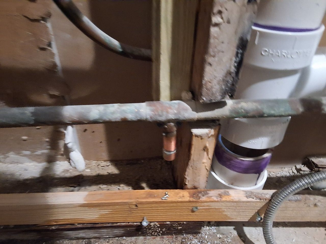 Under-floor plumbing pipes and wooden joists in a crawl space