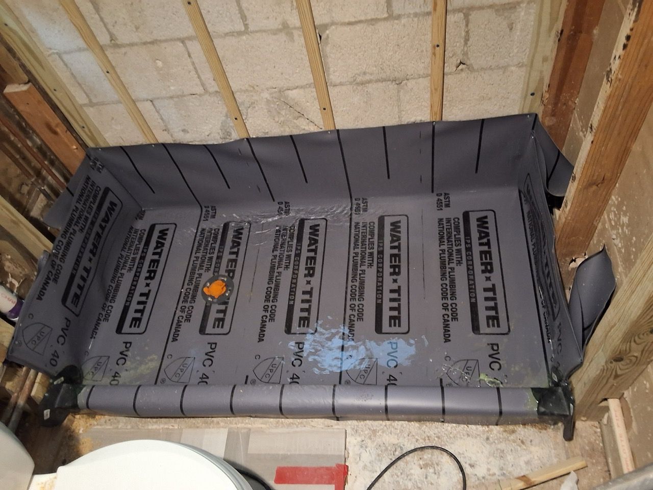 Gray insulation board installed in a small unfinished wall recess with exposed wood framing.