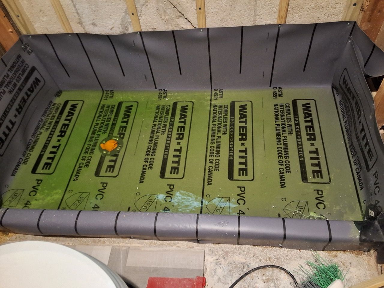 Green waterproof insulation board installed inside a framed wall cavity with gray foam trim.