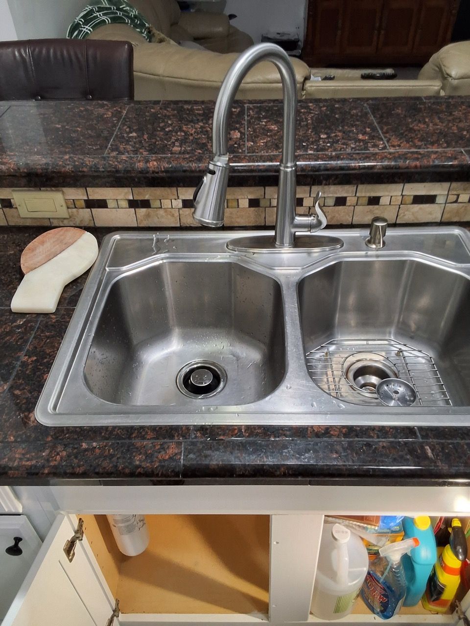 Kitchen sink with double basins, chrome faucet, and granite countertop.