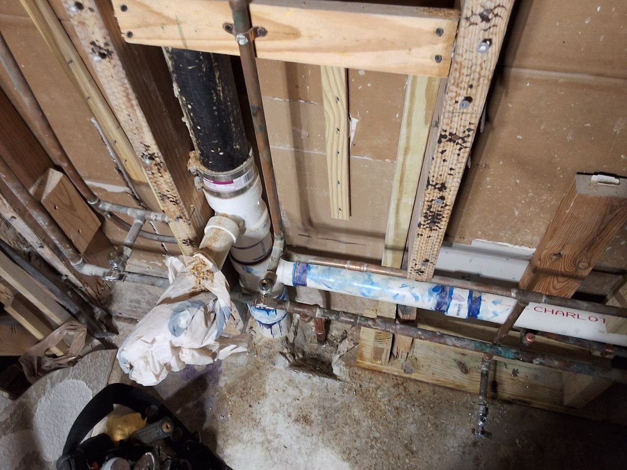 Exposed wall plumbing with PVC pipes and fittings in an unfinished utility area