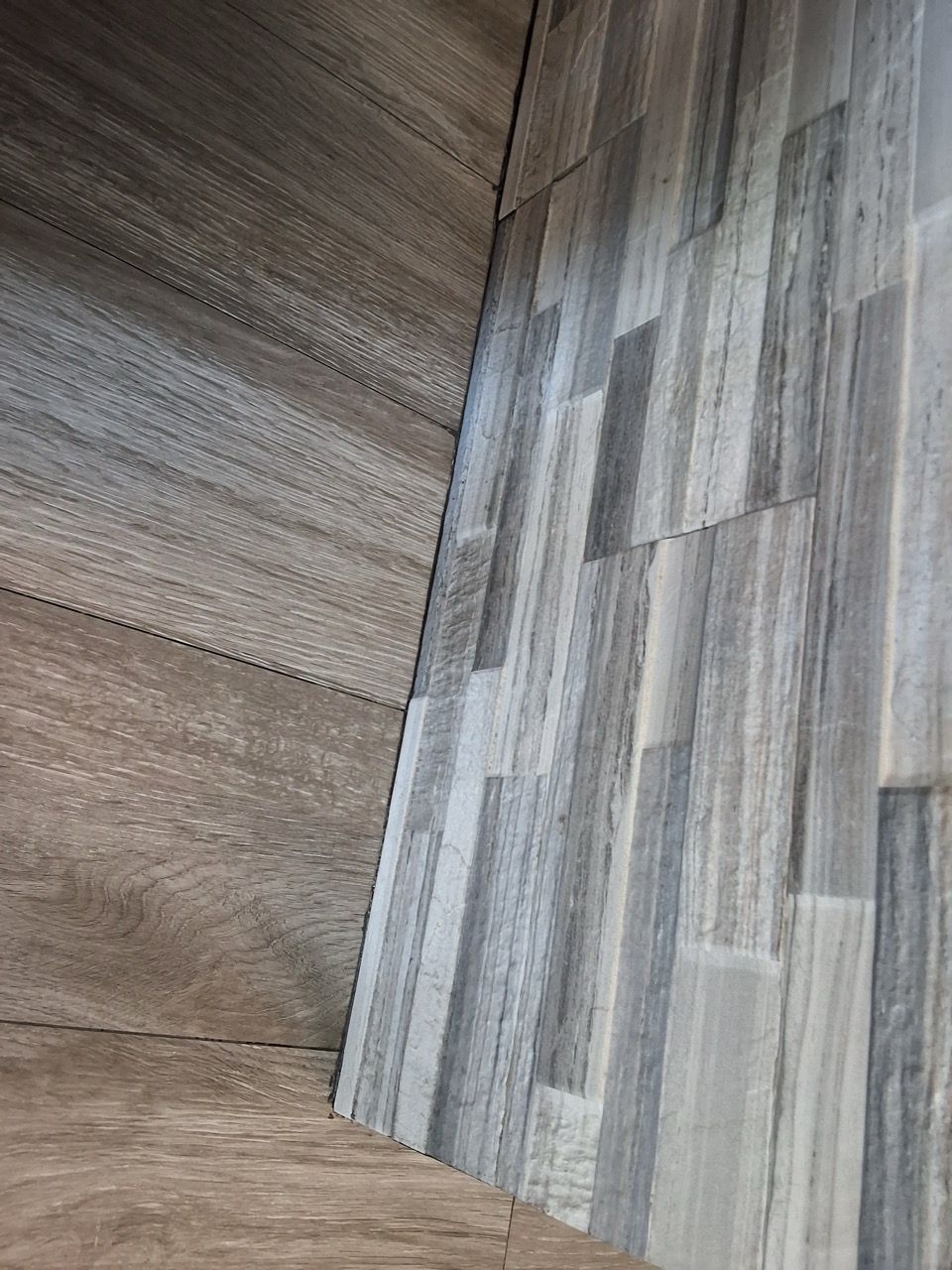 Close-up of a striped wood floor meeting a textured brown wall corner