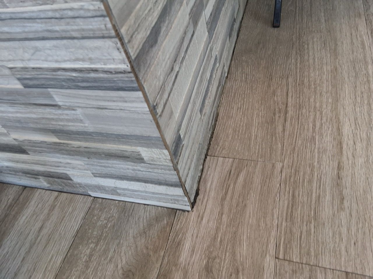 Gray tiled counter corner on a wood-look floor next to a wall