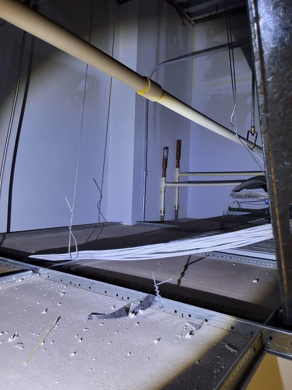 Broken glass and debris on a floor beside a tilted metal structure in an industrial interior.