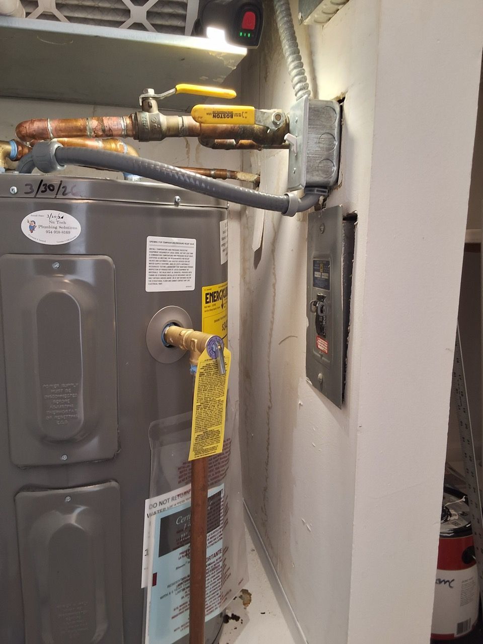 Utility closet with furnace and water heater pipes, including a yellow gas line handle.
