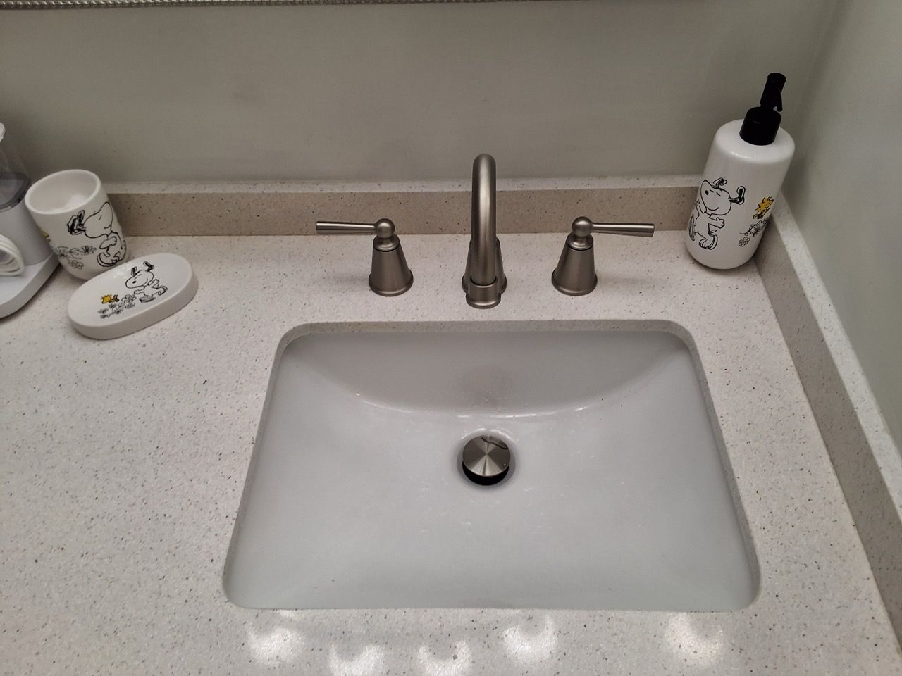 Bathroom sink with white countertop, chrome faucet, and soap dispenser on the right.