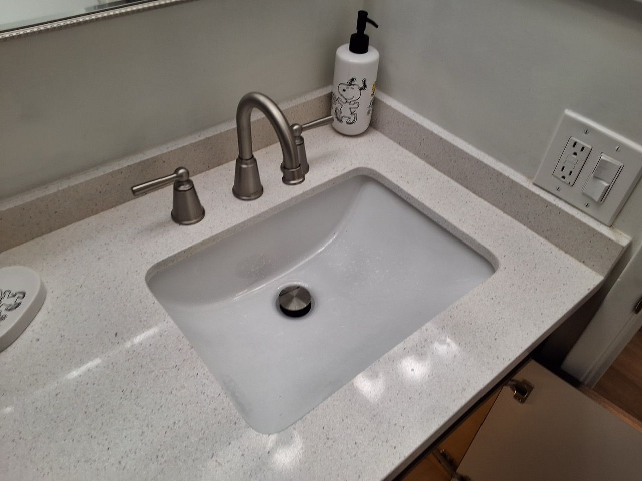 Modern bathroom sink with chrome faucet, soap dispenser, and granite countertop