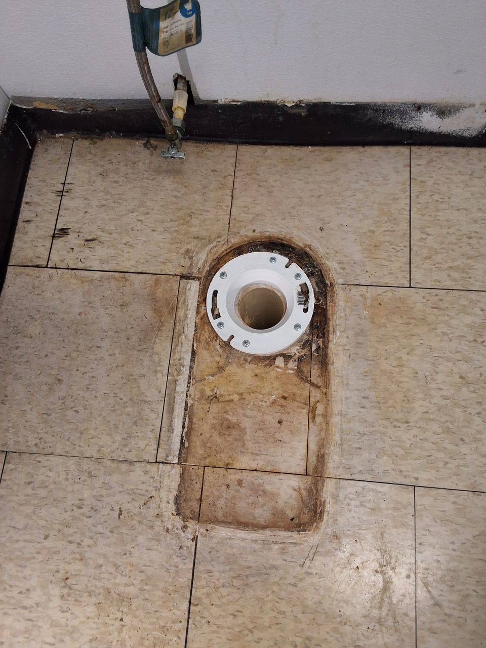Bathroom floor with a toilet drain and stained tile around it