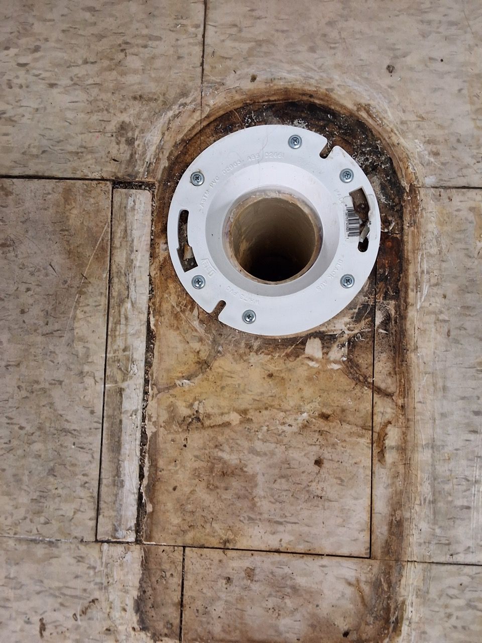 White pipe flange set into a weathered concrete wall, with a dark circular opening at the center.