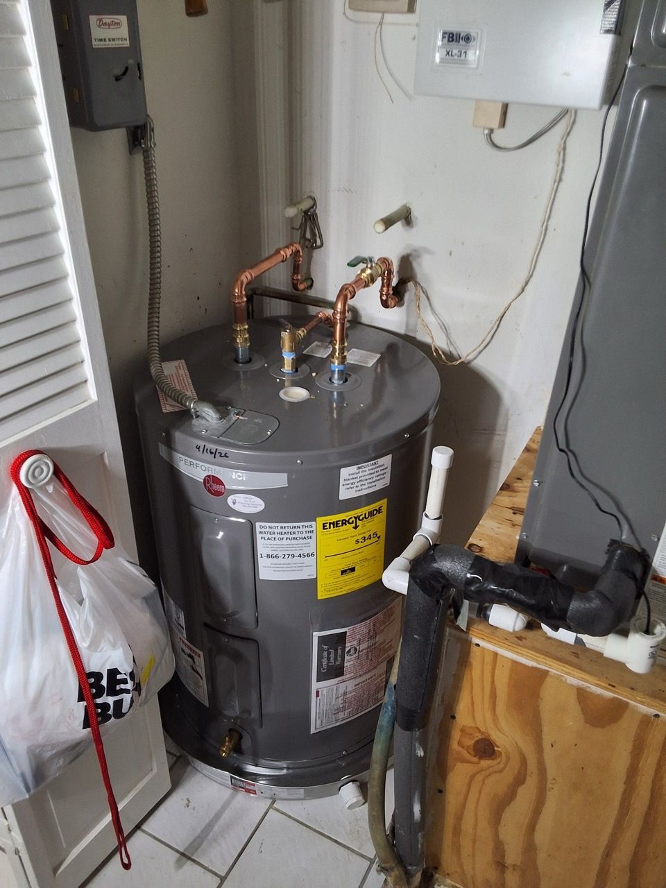 Water heater in a utility closet with pipes, valves, and nearby wiring.
