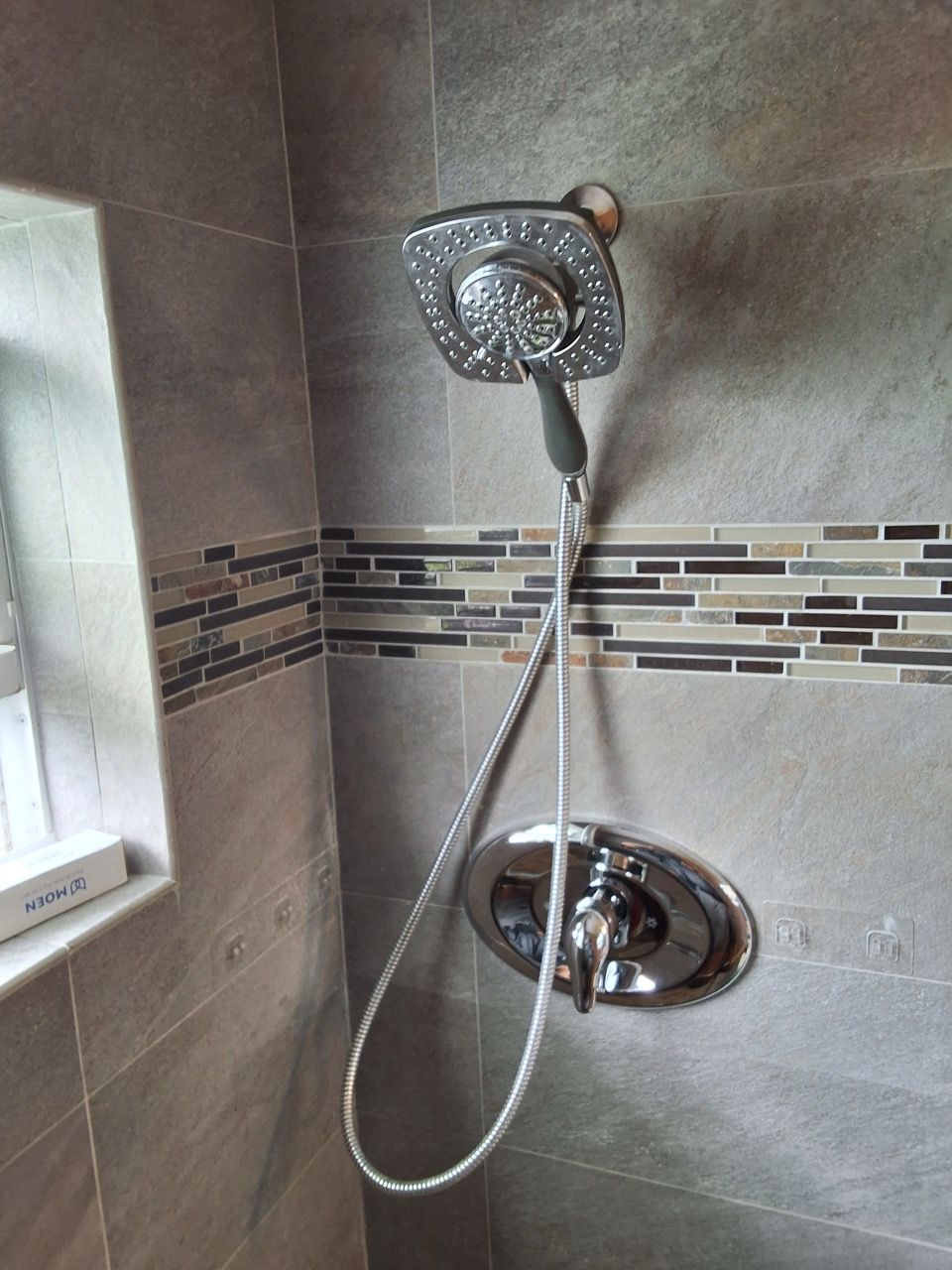 Chrome showerhead and handheld shower in a tiled bathroom corner