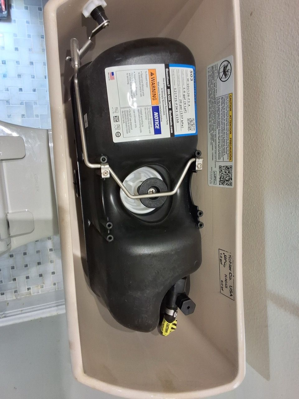 Black compressor unit inside a white appliance compartment with labels and wiring.