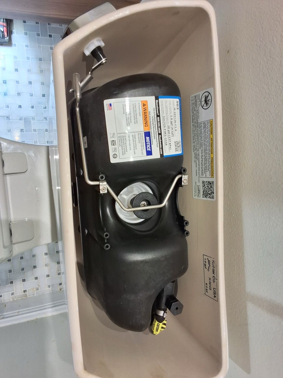 Black cylindrical tank with labels and tubing mounted inside a beige enclosure.