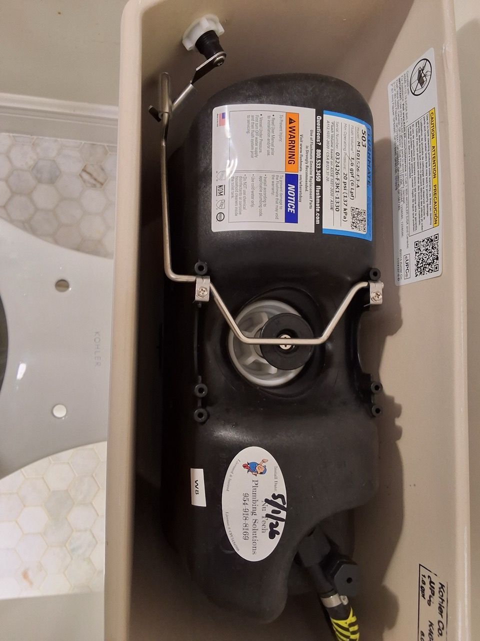 Black water heater with pipes and labels installed in a utility closet or bathroom cabinet.
