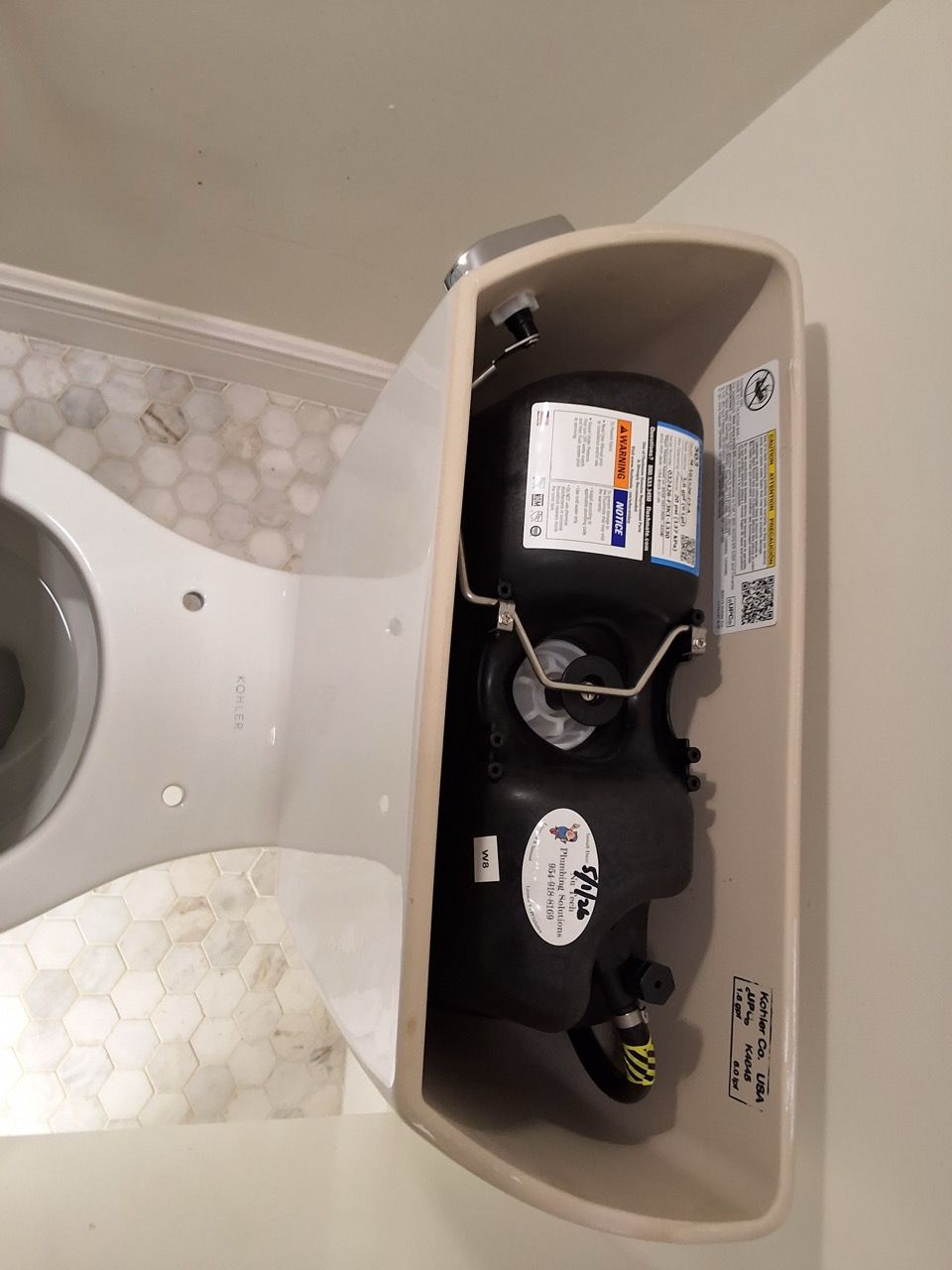 Open cabinet under sink showing plumbing and cleaning supplies behind a curved white countertop.