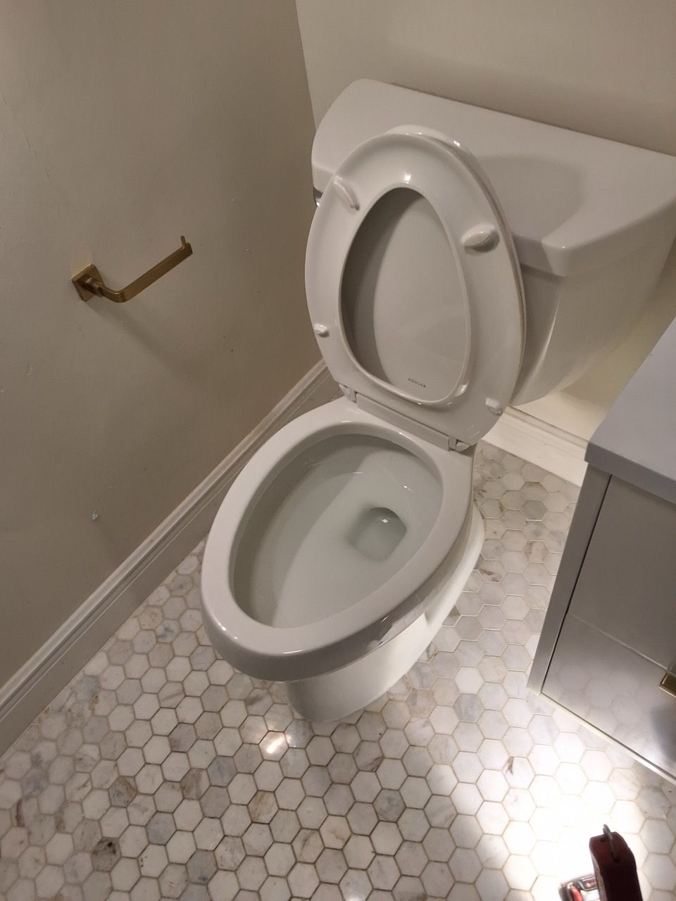Small bathroom with an open toilet, white hex tile floor, and a grab bar on the wall.