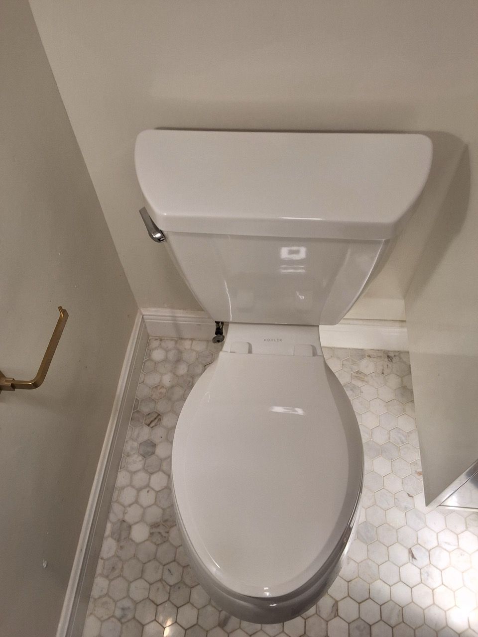 White toilet in a small tiled bathroom, viewed from above.