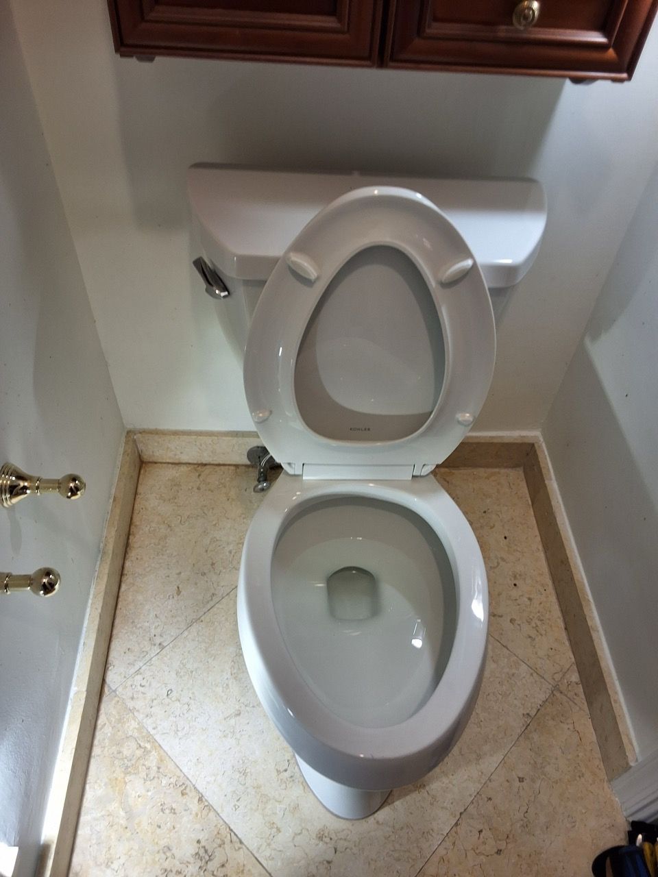 Small bathroom with an open toilet and beige tiled floor.