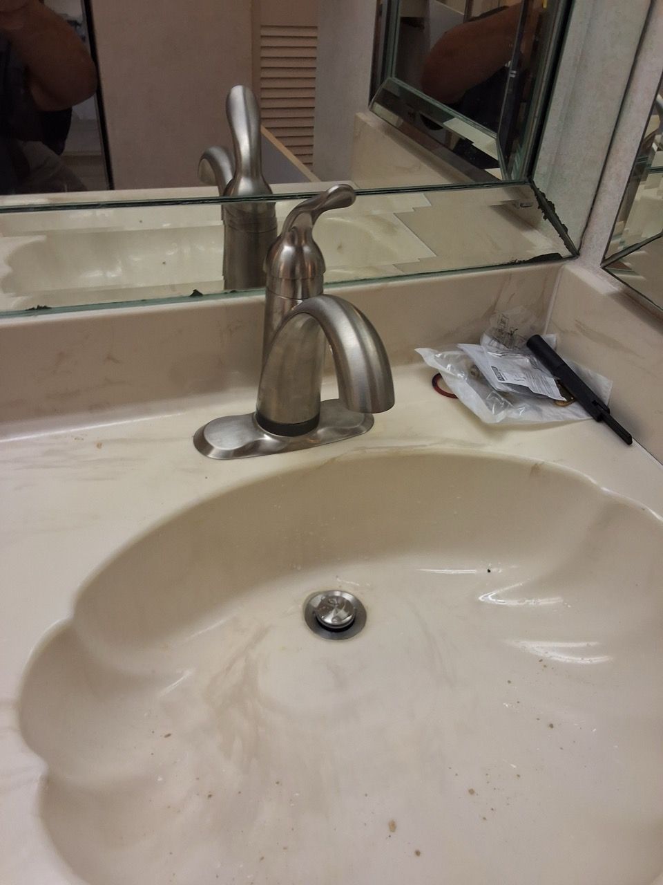 Bathroom sink with chrome faucet and mirror above, beige countertop, and a small item near the sink.