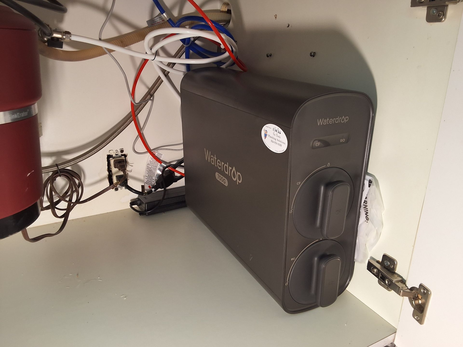 Black UPS battery backup unit installed inside a cabinet with cables and red cylinders nearby