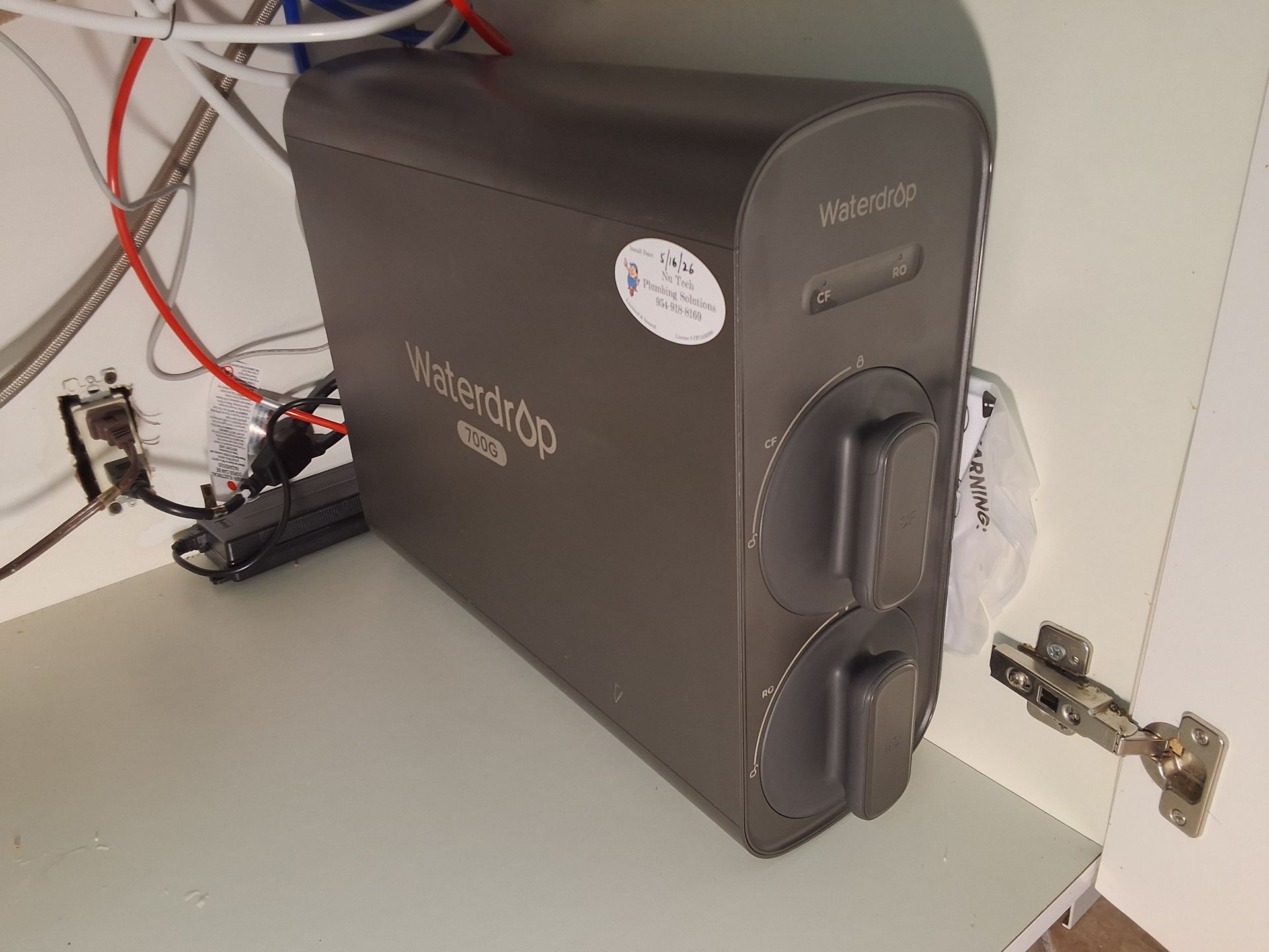 Black router/modem on a shelf with cables connected and a red wire beside it.